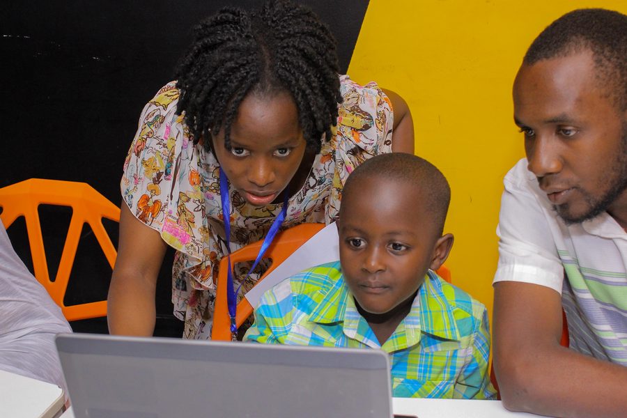 A young learner at a laptop with a facilitator helping during a Scratch coding session