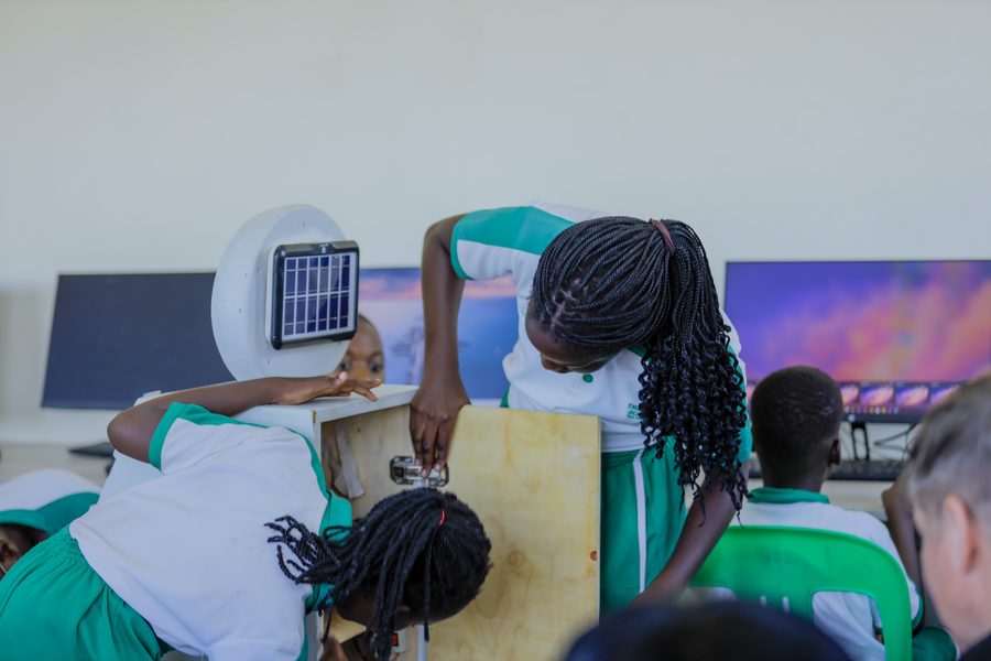 Two schoolgirls building a wooden robot with a solar panel